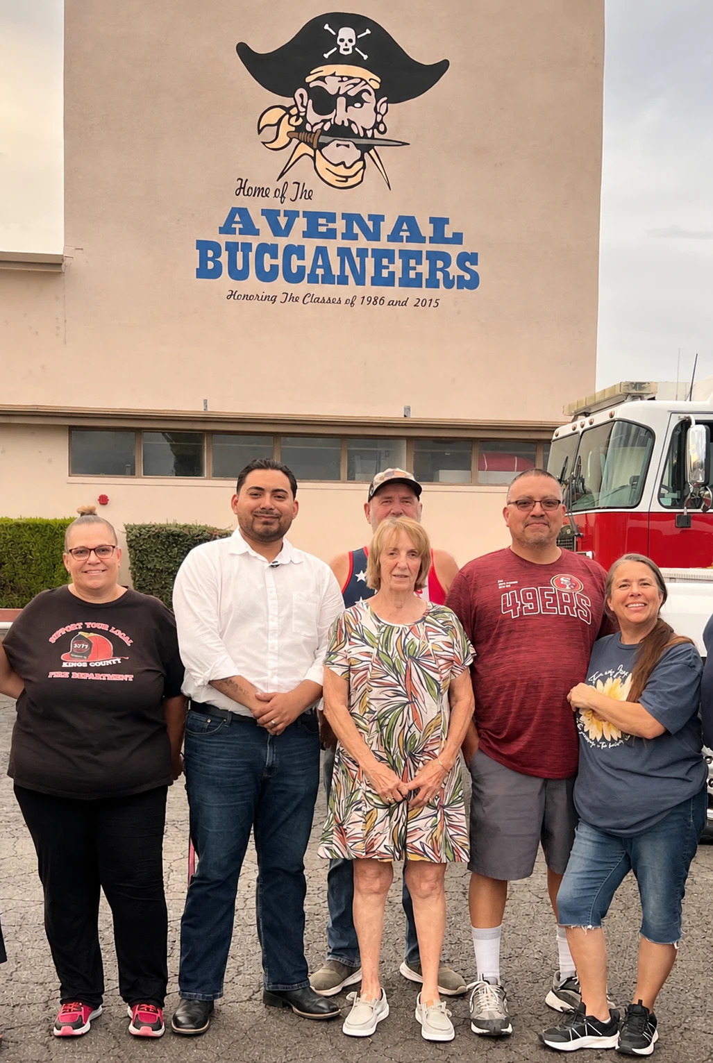 Guillermo with Avenal residents and a Kings County firefighter in front of the Avenal High School Buccaneers mural.