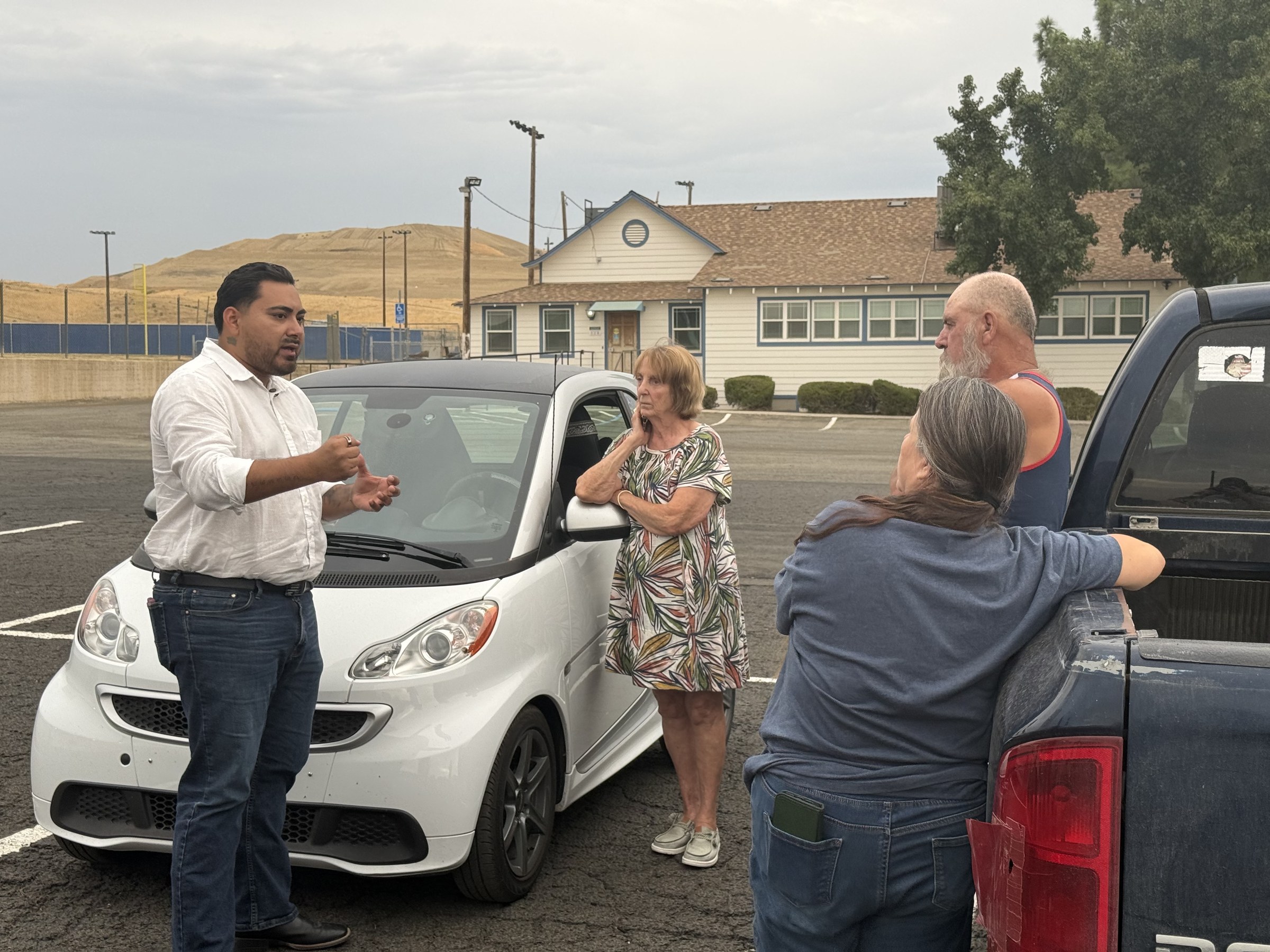 Guillermo talking with residents in a parking lot in Avenal.